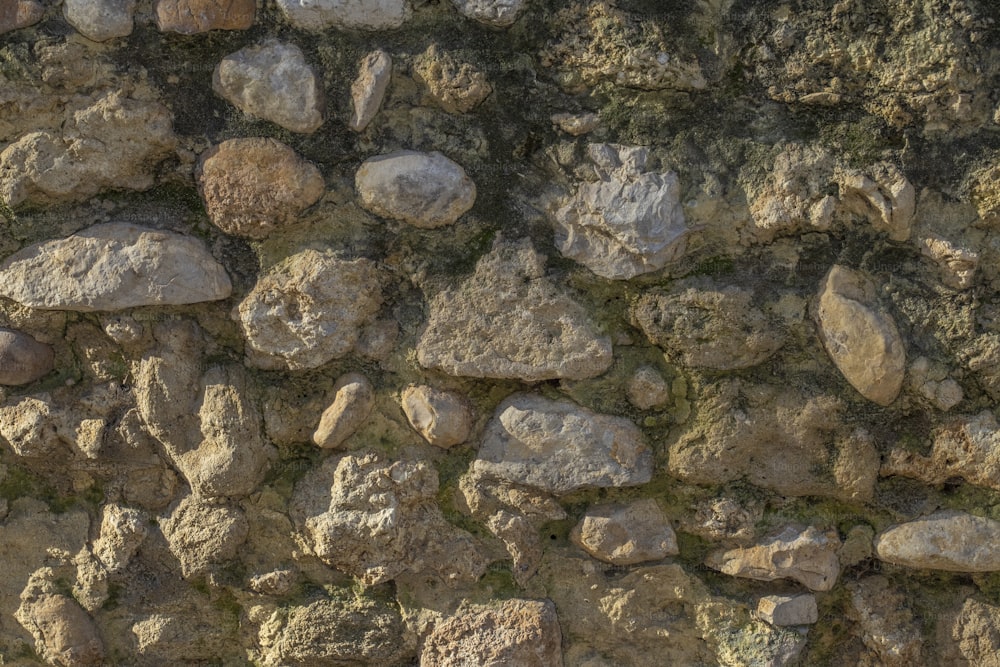 a stone wall with rocks and moss growing on it