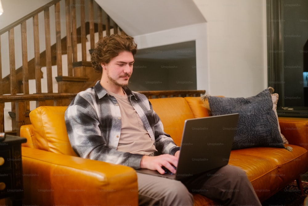 Ein Mann sitzt auf einer Couch und benutzt einen Laptop