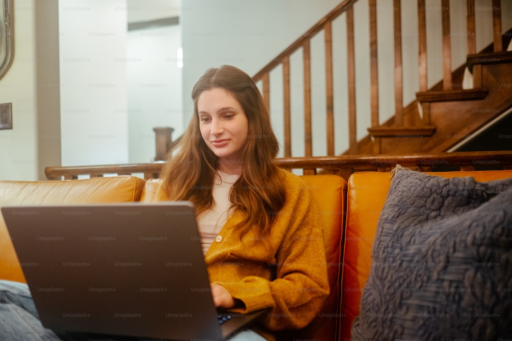 노트북 컴퓨터를 사용하여 소��파에 앉아 있는 여자