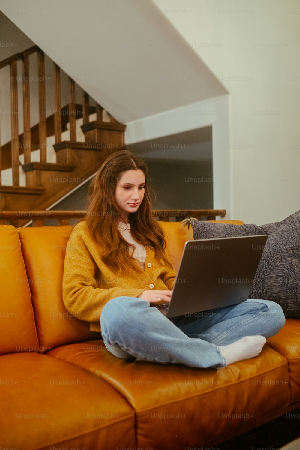 Una mujer sentada en un sofá usando una computadora portátil