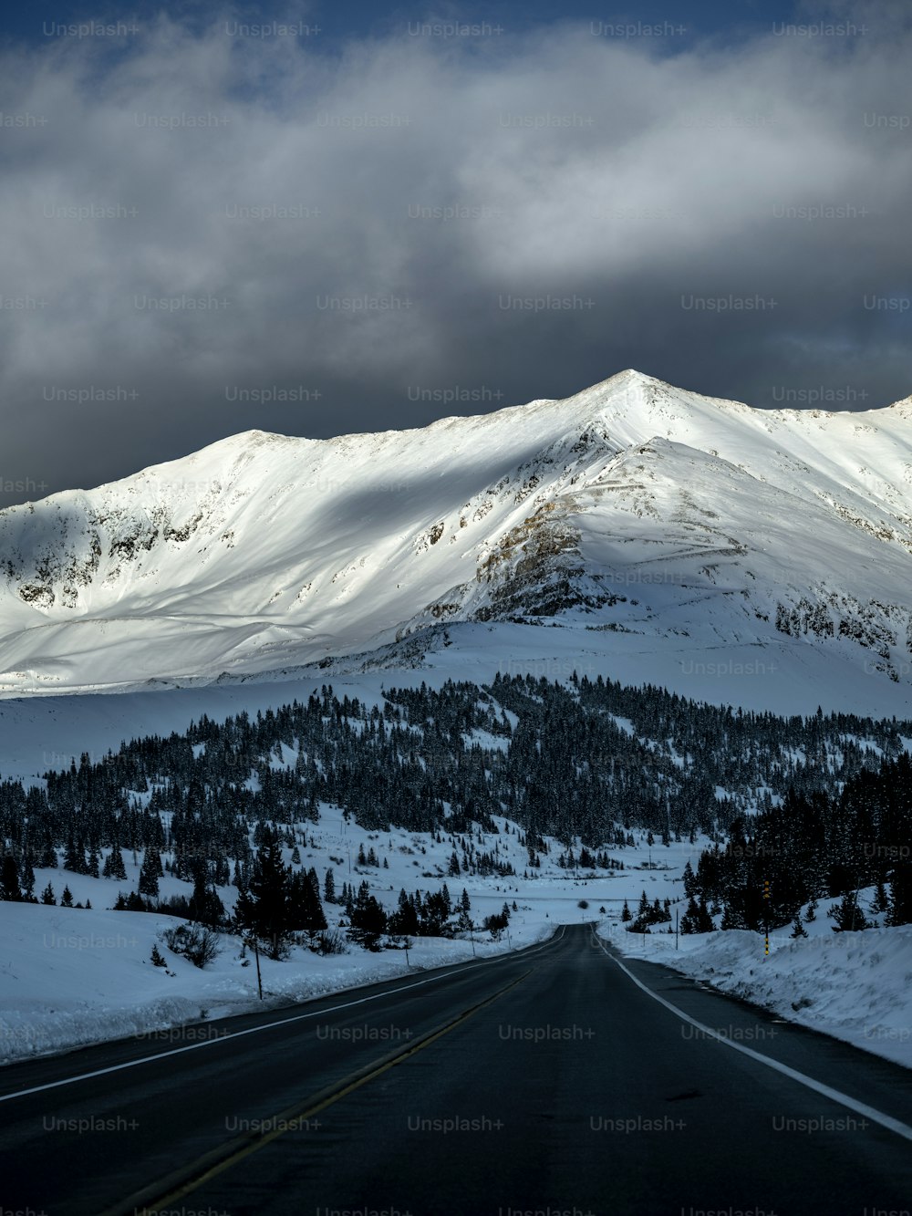 uma montanha coberta de neve com uma estrada em primeiro plano
