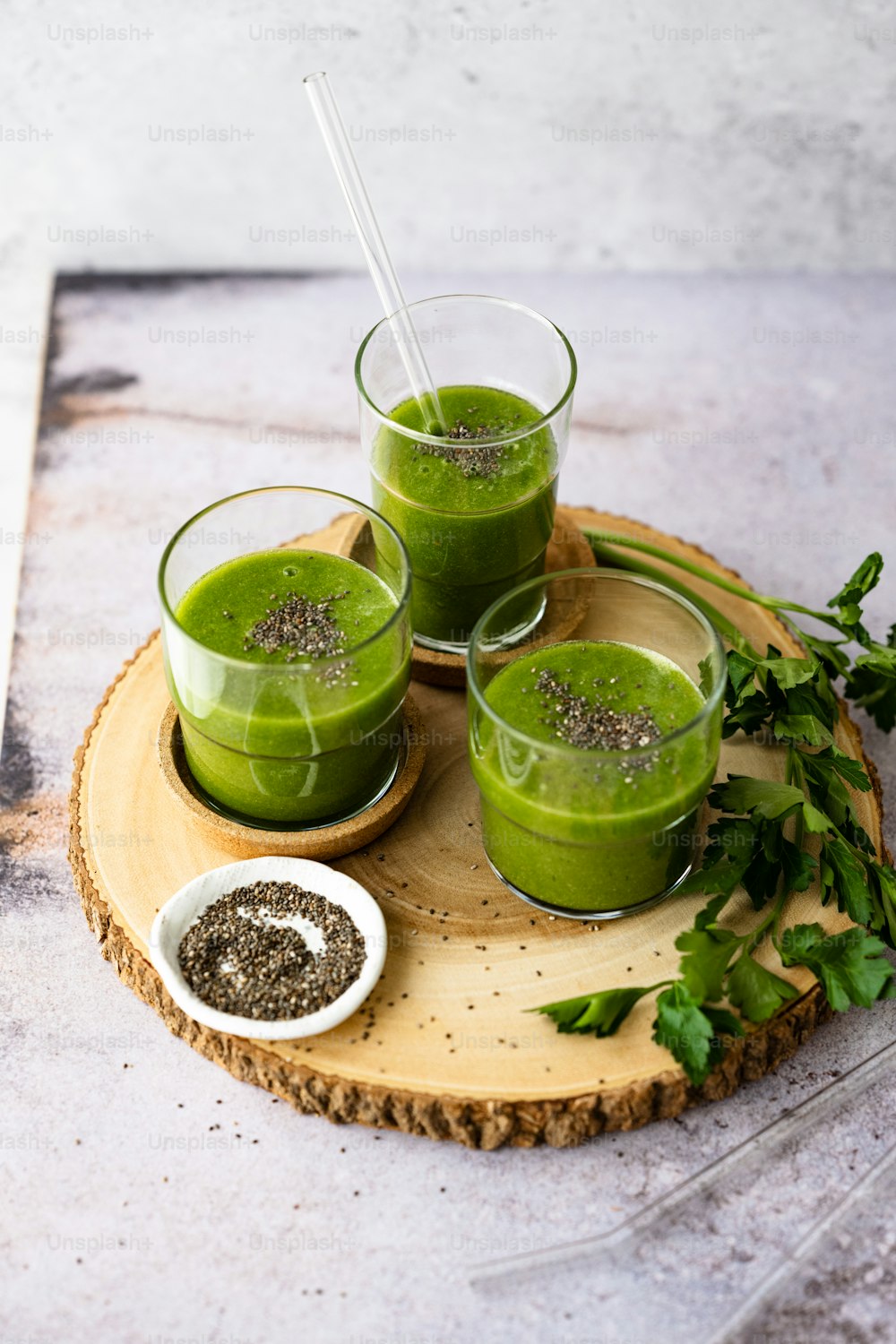 three glasses of green smoothie on a wooden tray