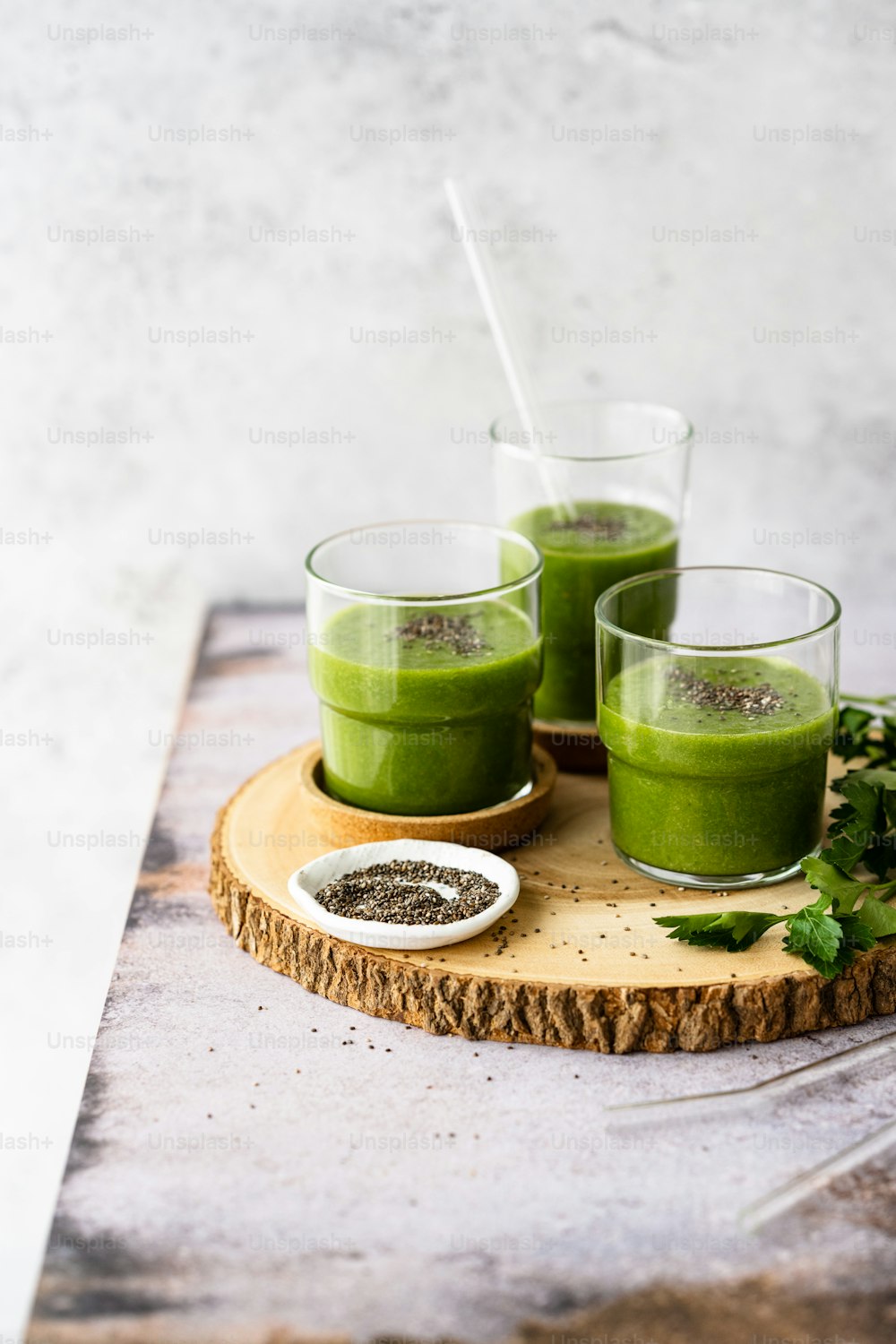 três copos de smoothie verde em uma bandeja de madeira