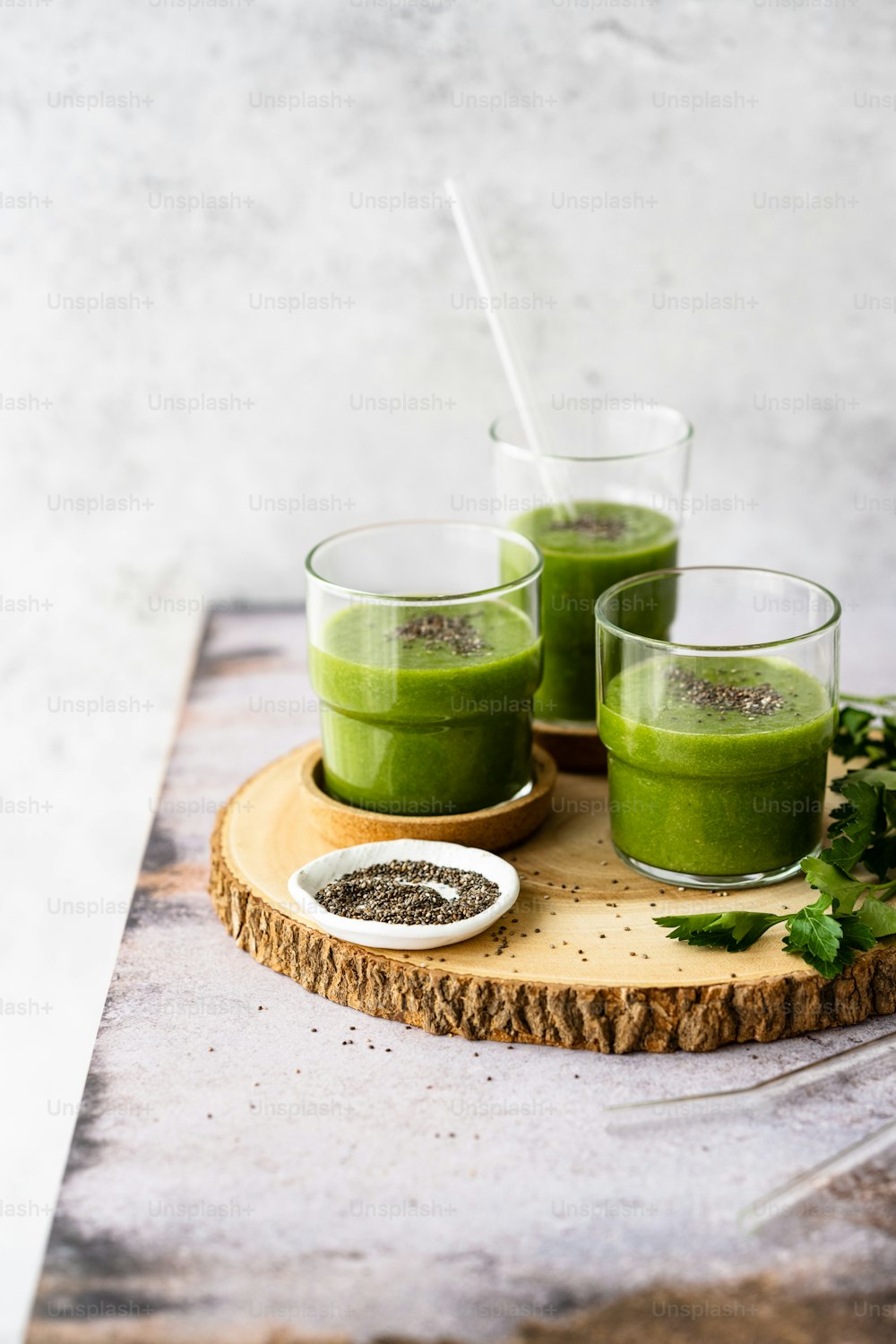 three glasses of green smoothie on a wooden tray
