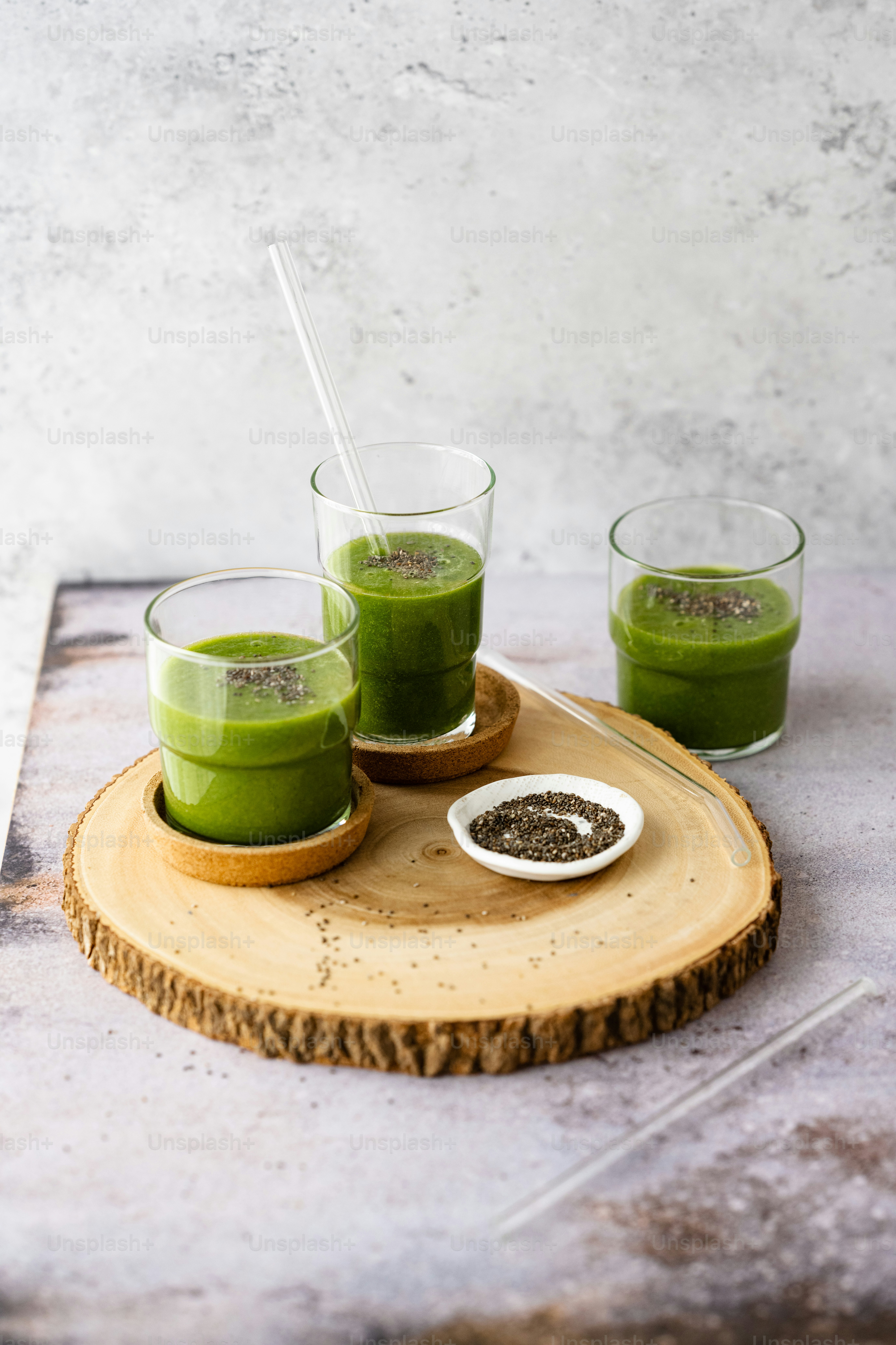 three glasses of green smoothie on a wooden tray