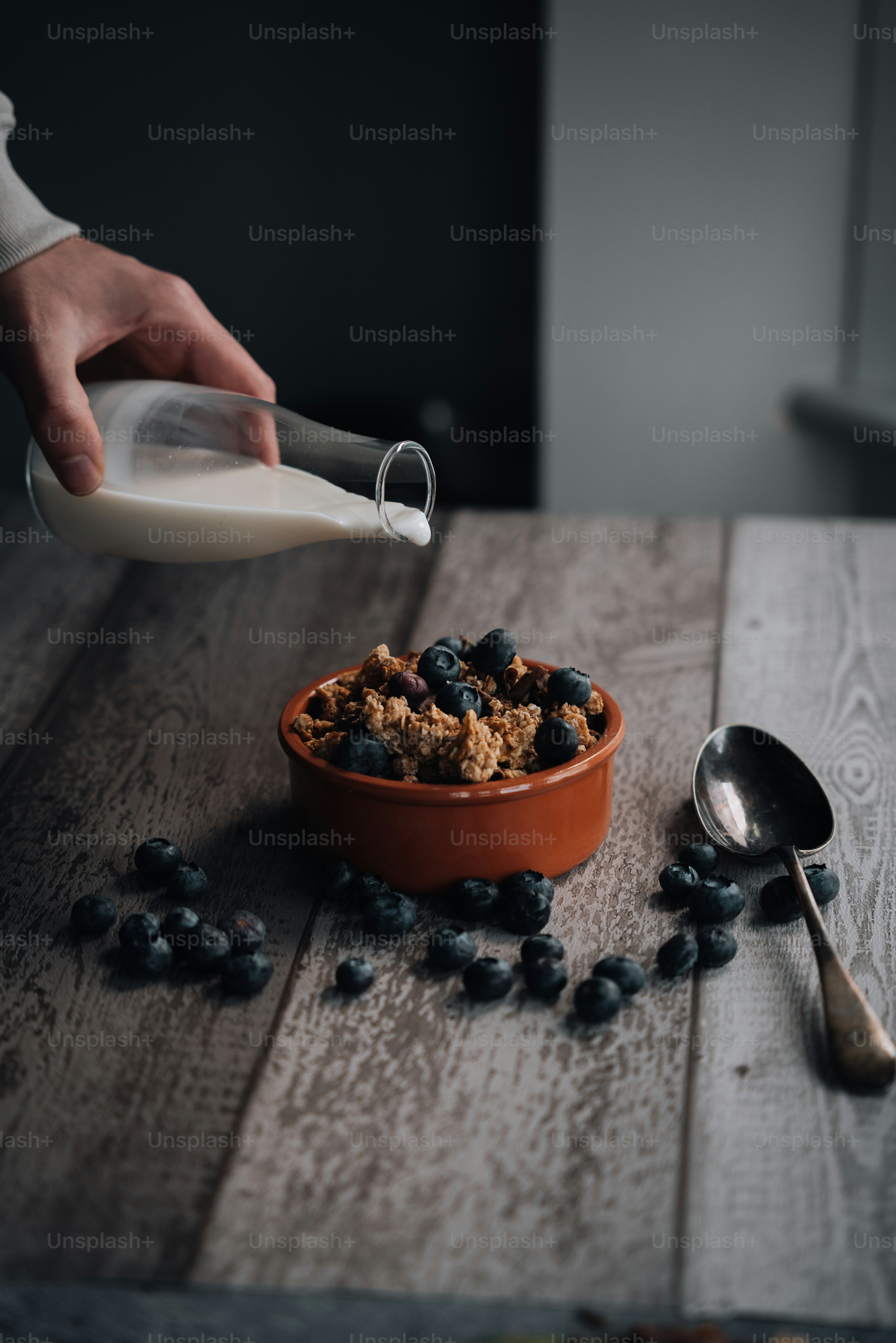 a person pouring milk into a bowl of cereal