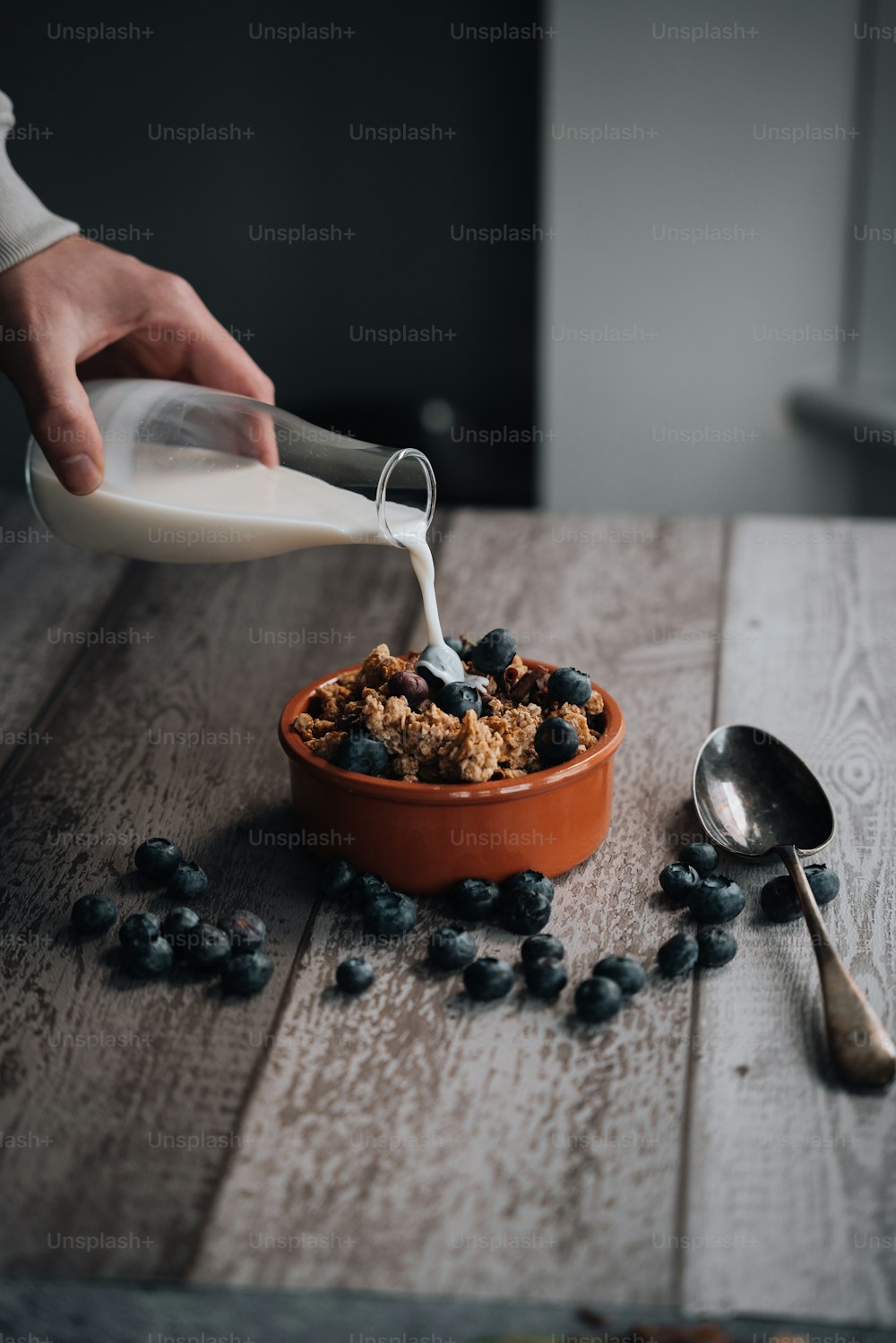 a person pouring milk into a bowl of cereal