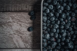 a metal container filled with blueberries on top of a wooden table