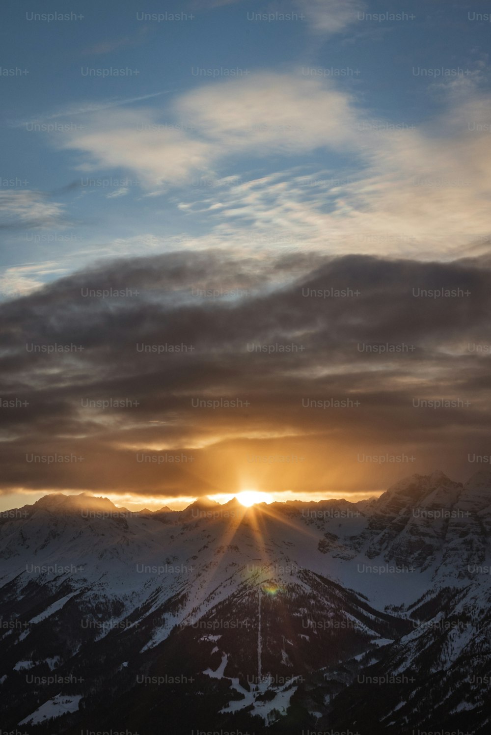 the sun is setting over the snowy mountains