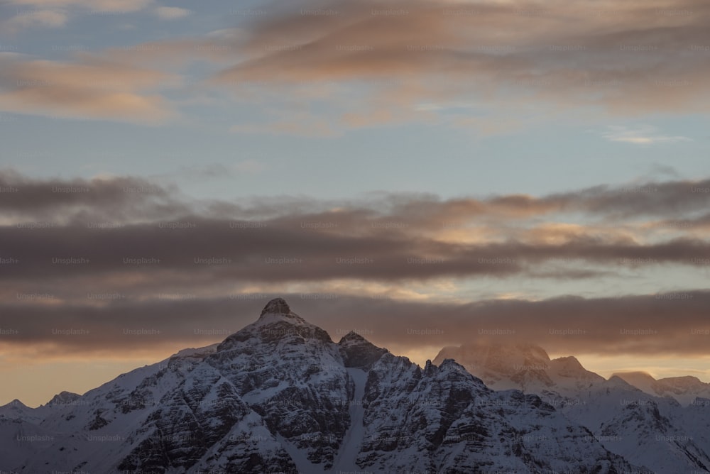 a large mountain covered in snow under a cloudy sky