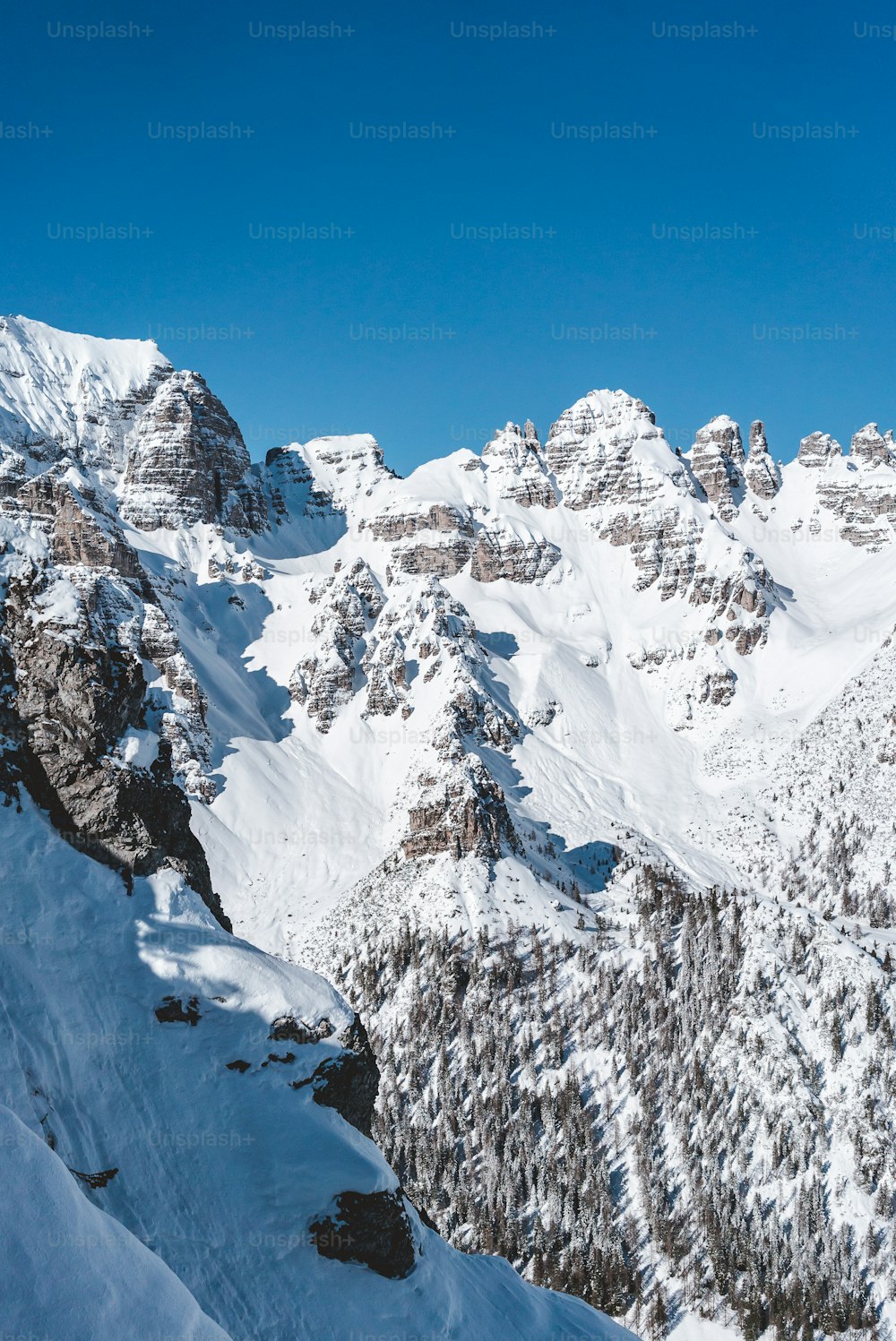 Ein Mann fährt auf Skiern die Seite eines schneebedeckten Berges hinunter