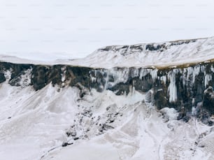 a mountain covered in ice and snow next to a cliff