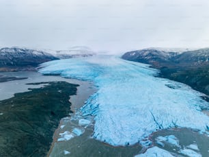 an aerial view of a glacier with mountains in the background