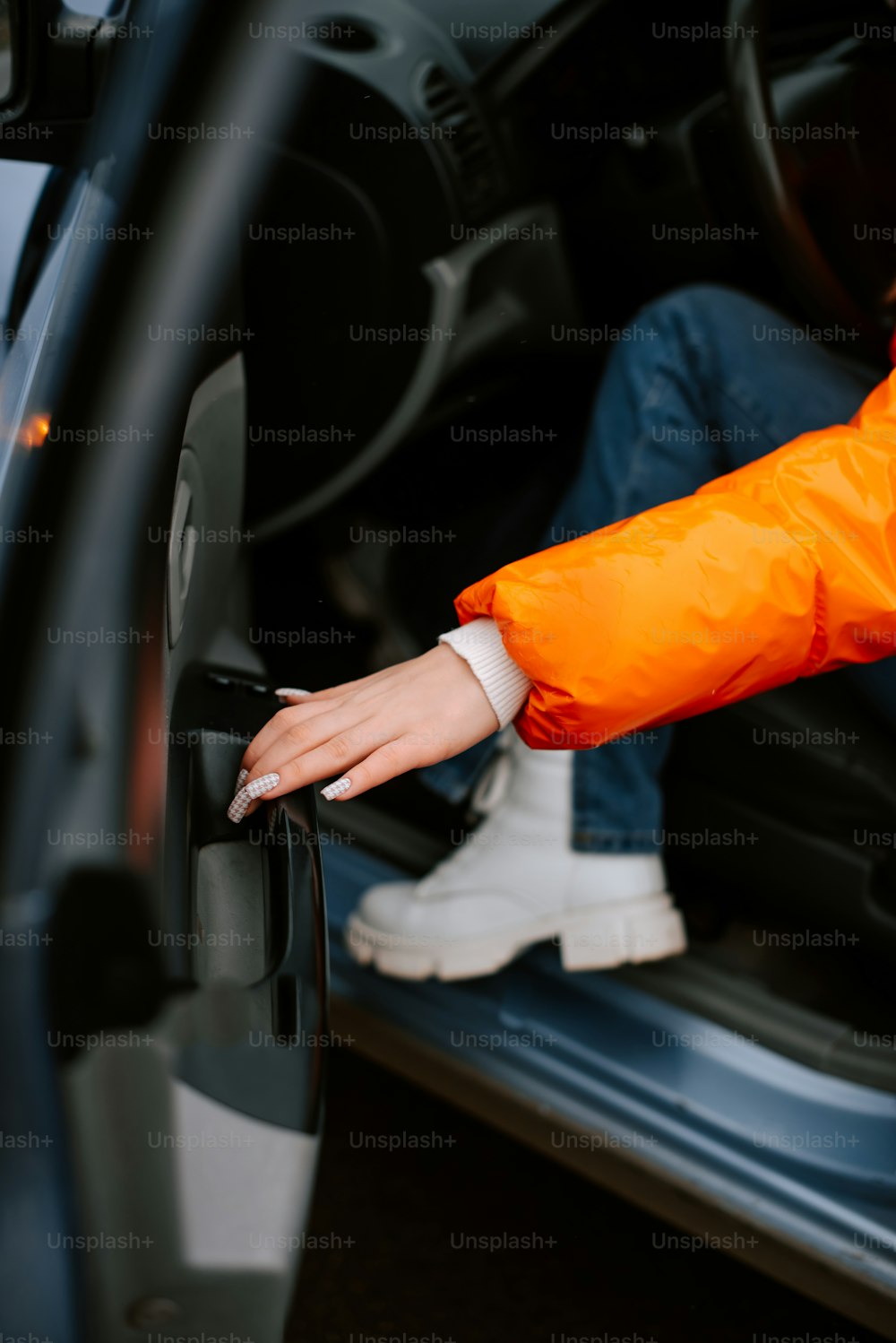 a person in an orange jacket opening a car door