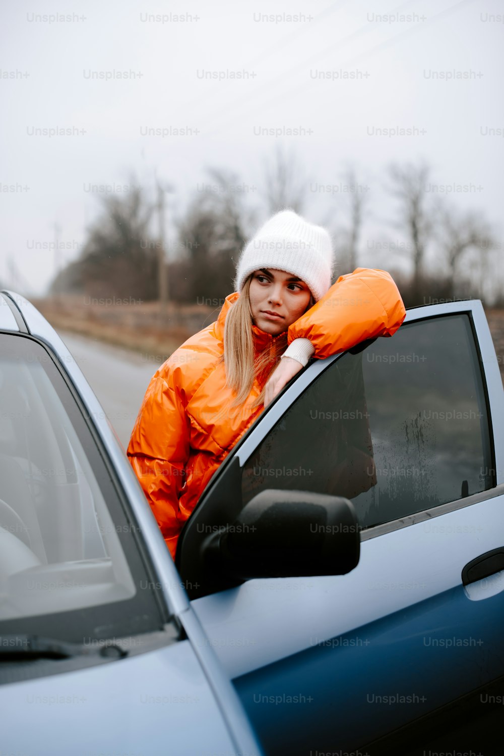 a woman in an orange jacket leaning out of a car window