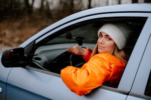 Une femme en veste orange conduisant une voiture bleue