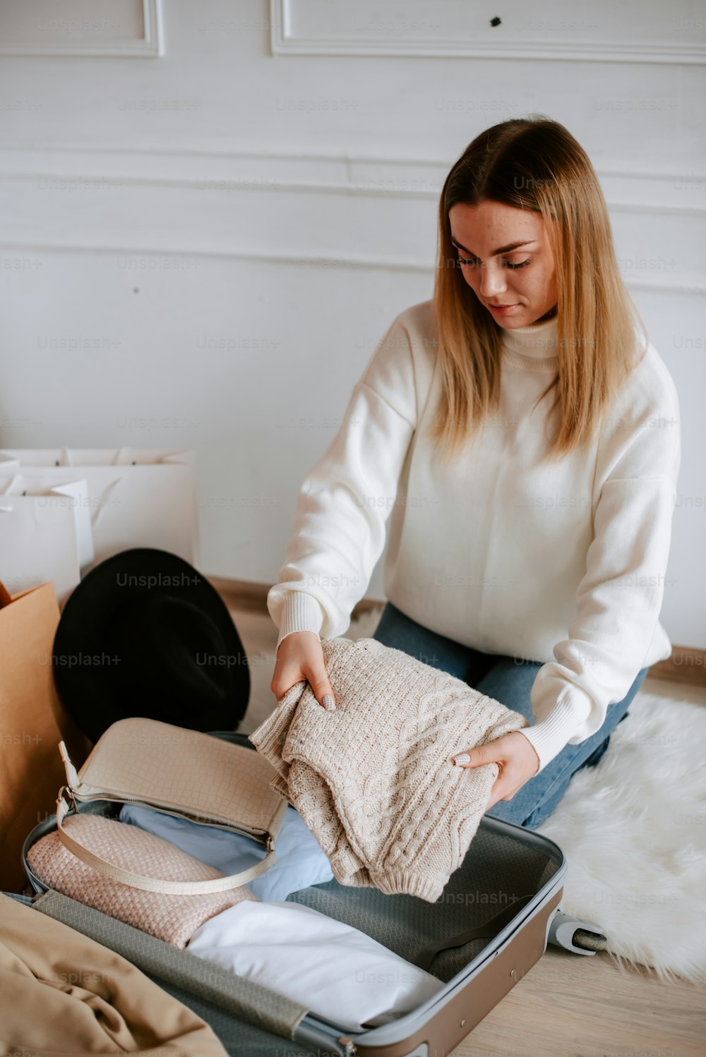 a woman is packing clothes in a suitcase