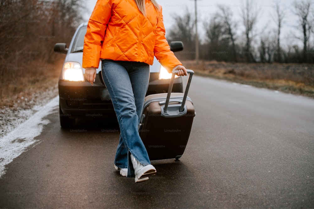 Una mujer caminando por la carretera con una maleta
