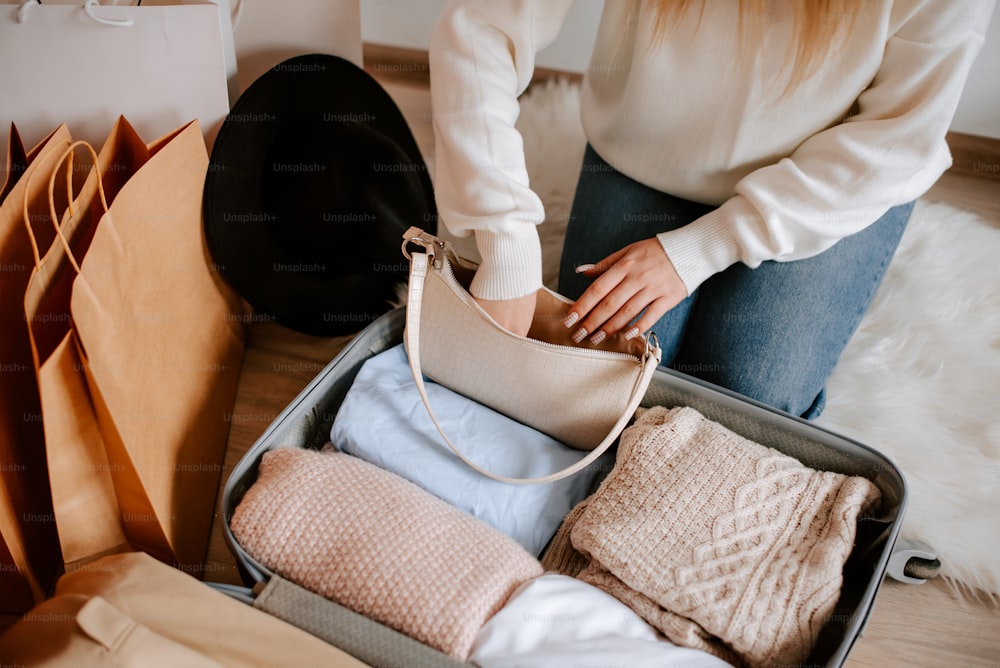 a woman is packing clothes in a suitcase