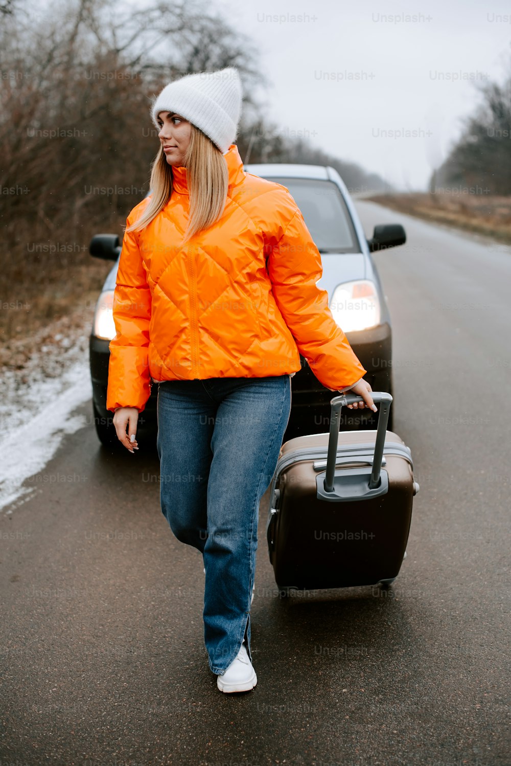 a woman walking down a road with a suitcase