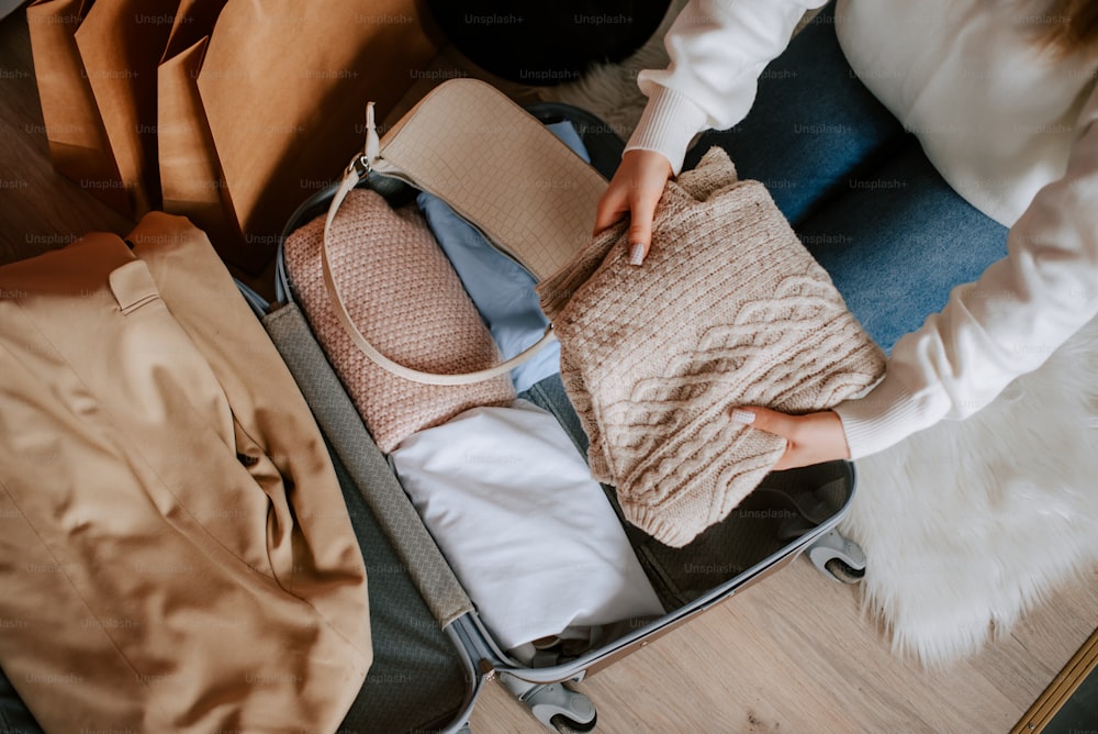 a woman is packing her suitcase with clothes