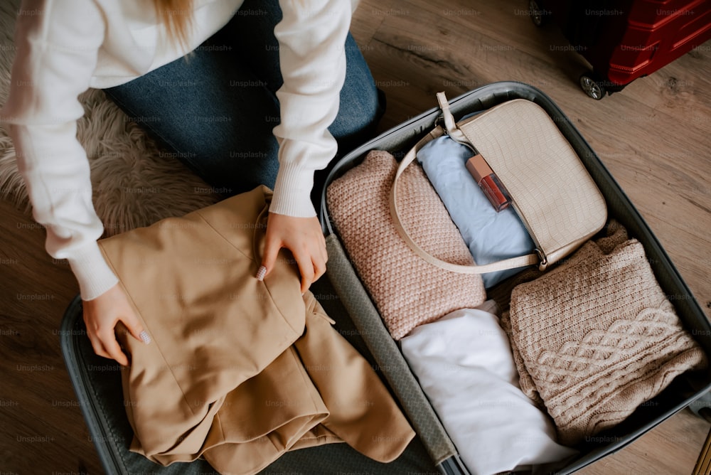 a woman sitting in a suitcase with clothes in it