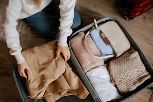 a woman sitting in a suitcase with clothes in it