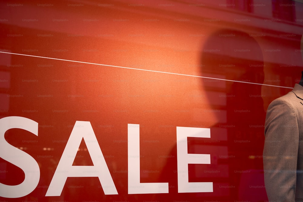 a man standing in front of a red sale sign