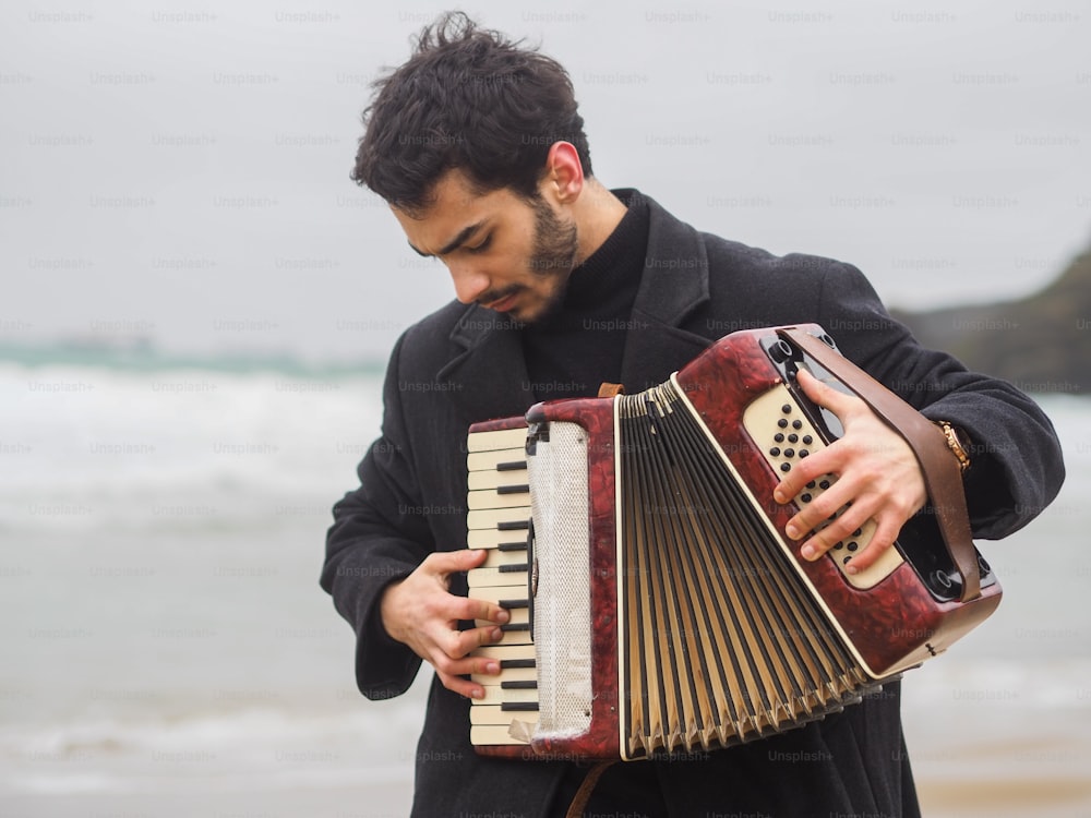 a man playing an accordion on the beach