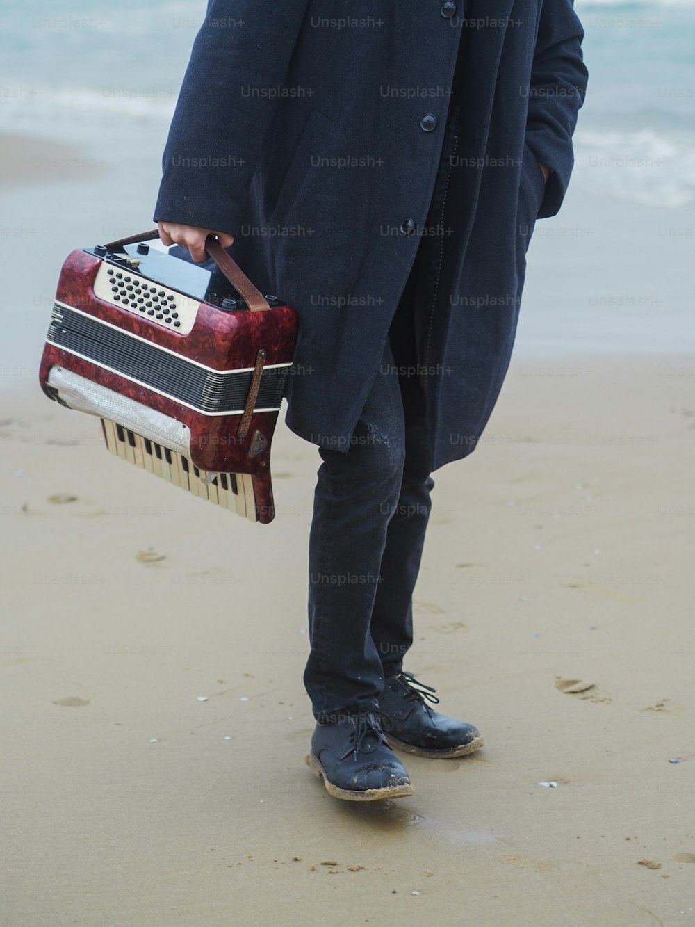 スーツケースを持ってビーチに立っている男性