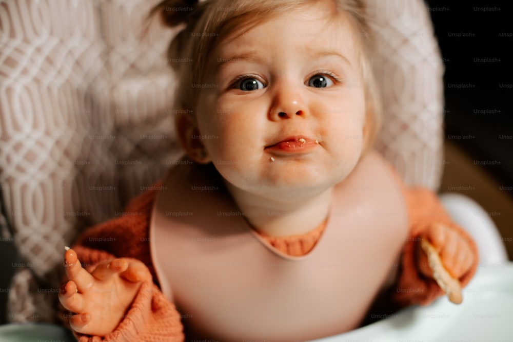 um bebê sentado em uma cadeira alta com comida na boca