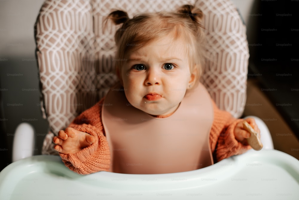 a little girl sitting in a high chair with a surprised look on her face