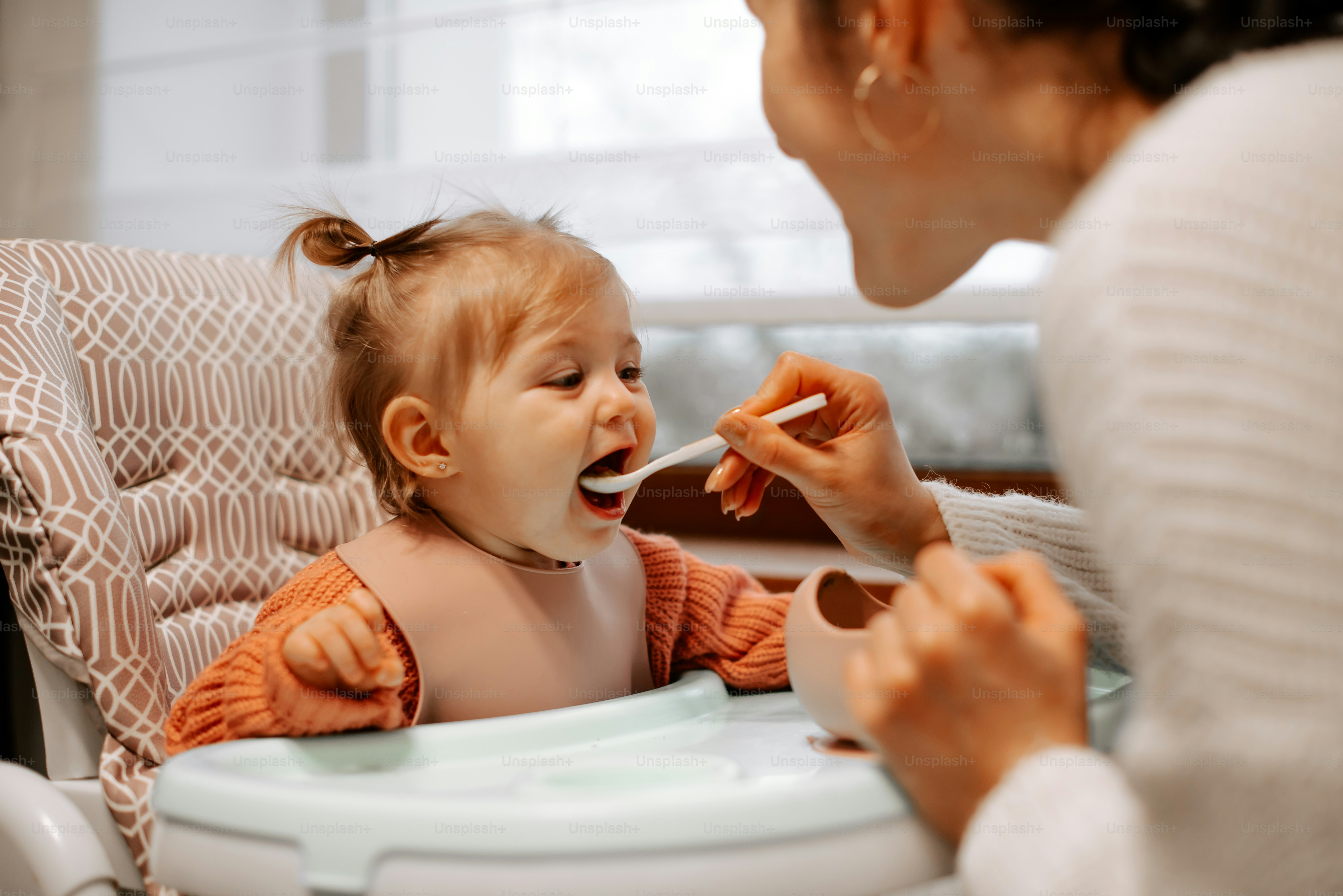 Eine Frau, die ein Baby mit einem Löffel füttert