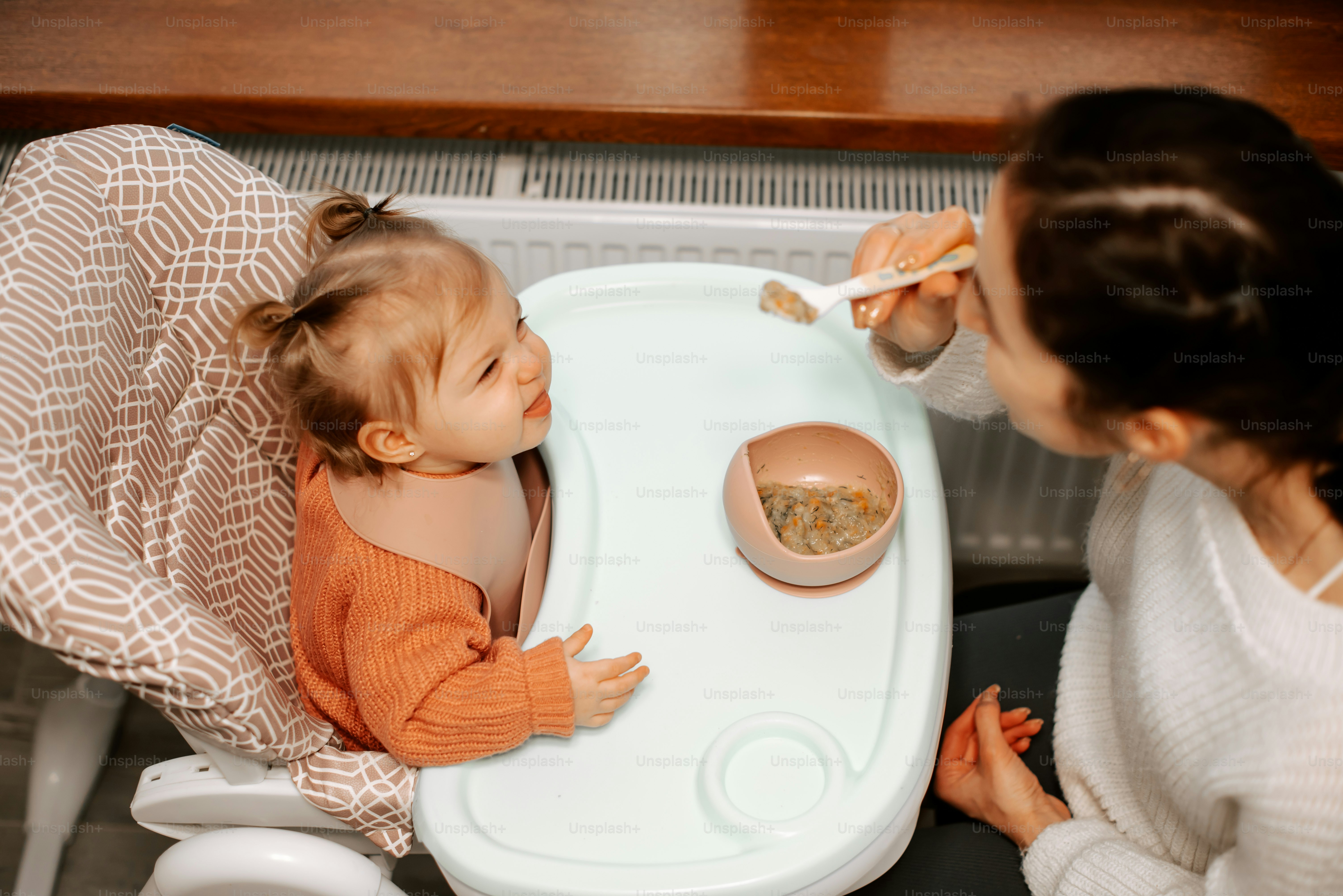 a woman feeding a baby in a high chair