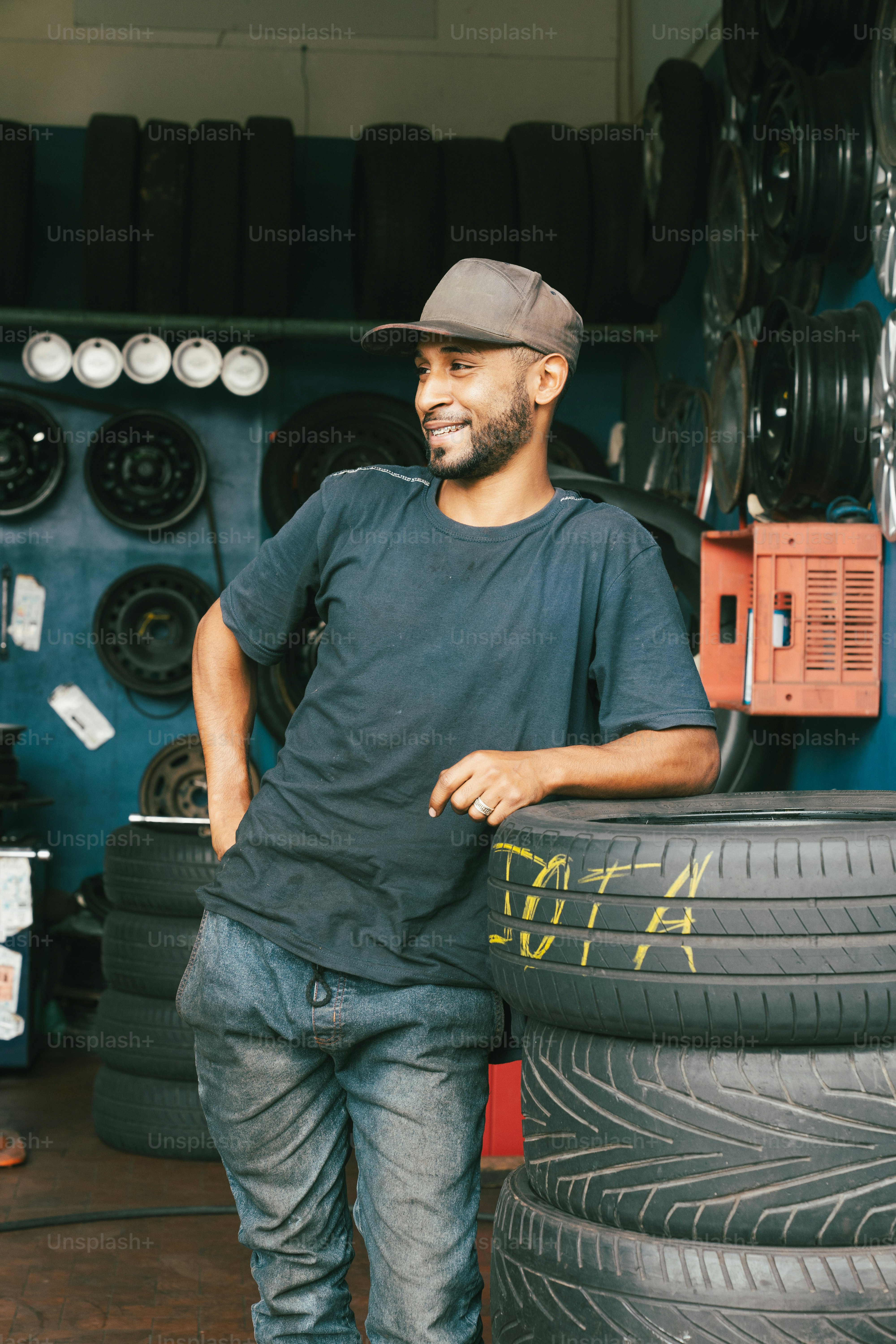 Un hombre parado junto a una pila de neumáticos