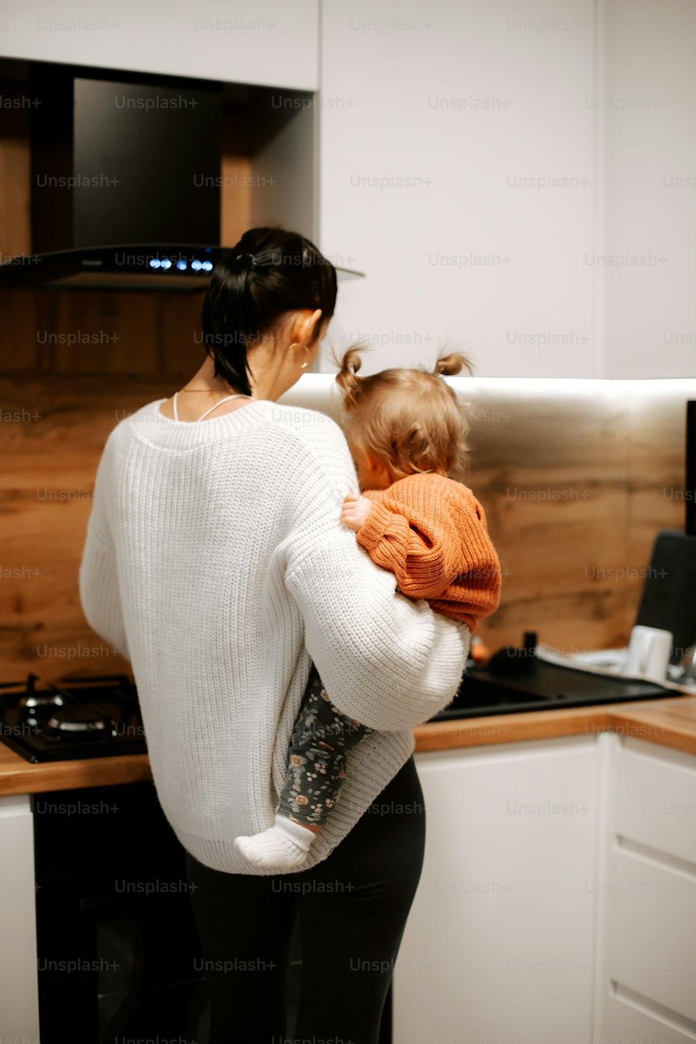 a woman holding a child in a kitchen