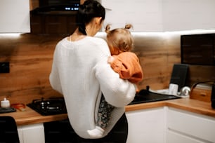 a woman holding a child in a kitchen