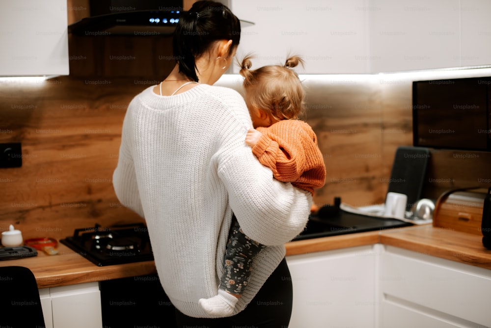 Una mujer sosteniendo a un niño en una cocina