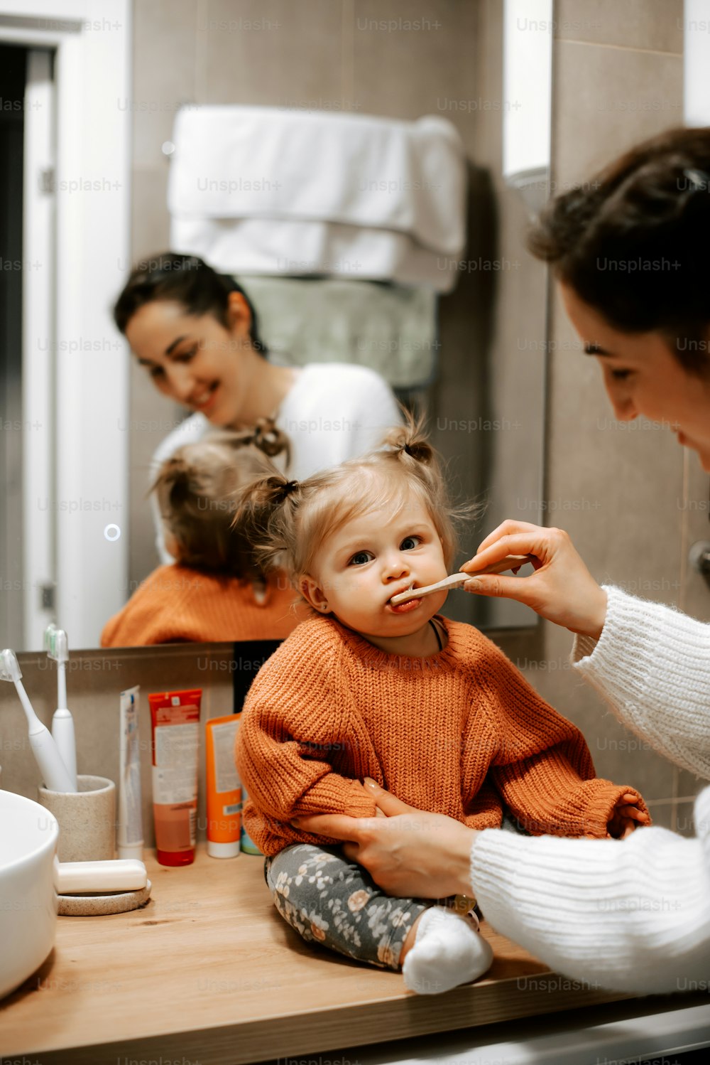 a woman brushing her teeth while sitting in front of a mirror