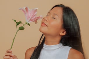 uma jovem cheirando uma flor rosa com os olhos fechados