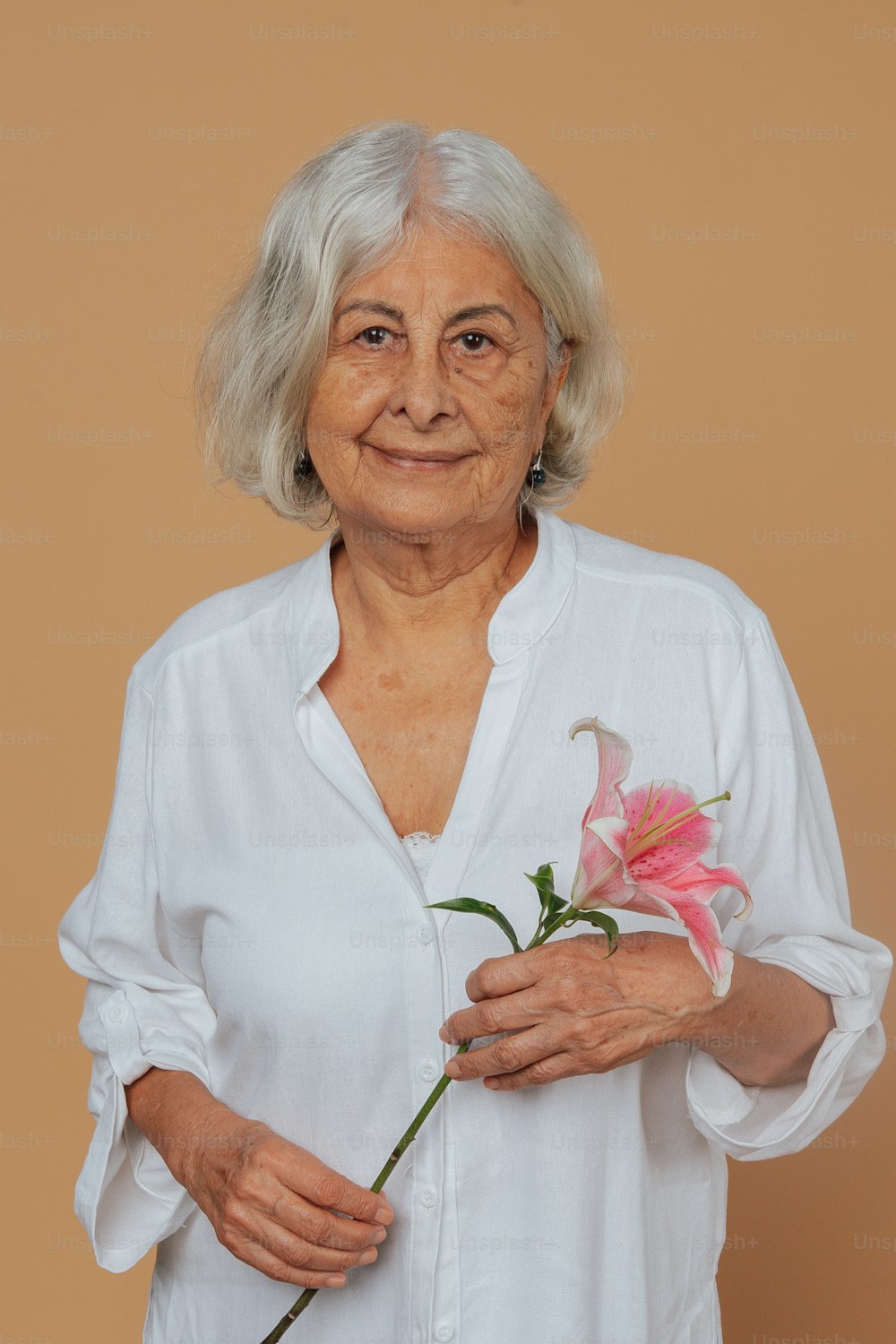 uma mulher mais velha segurando uma flor em suas mãos