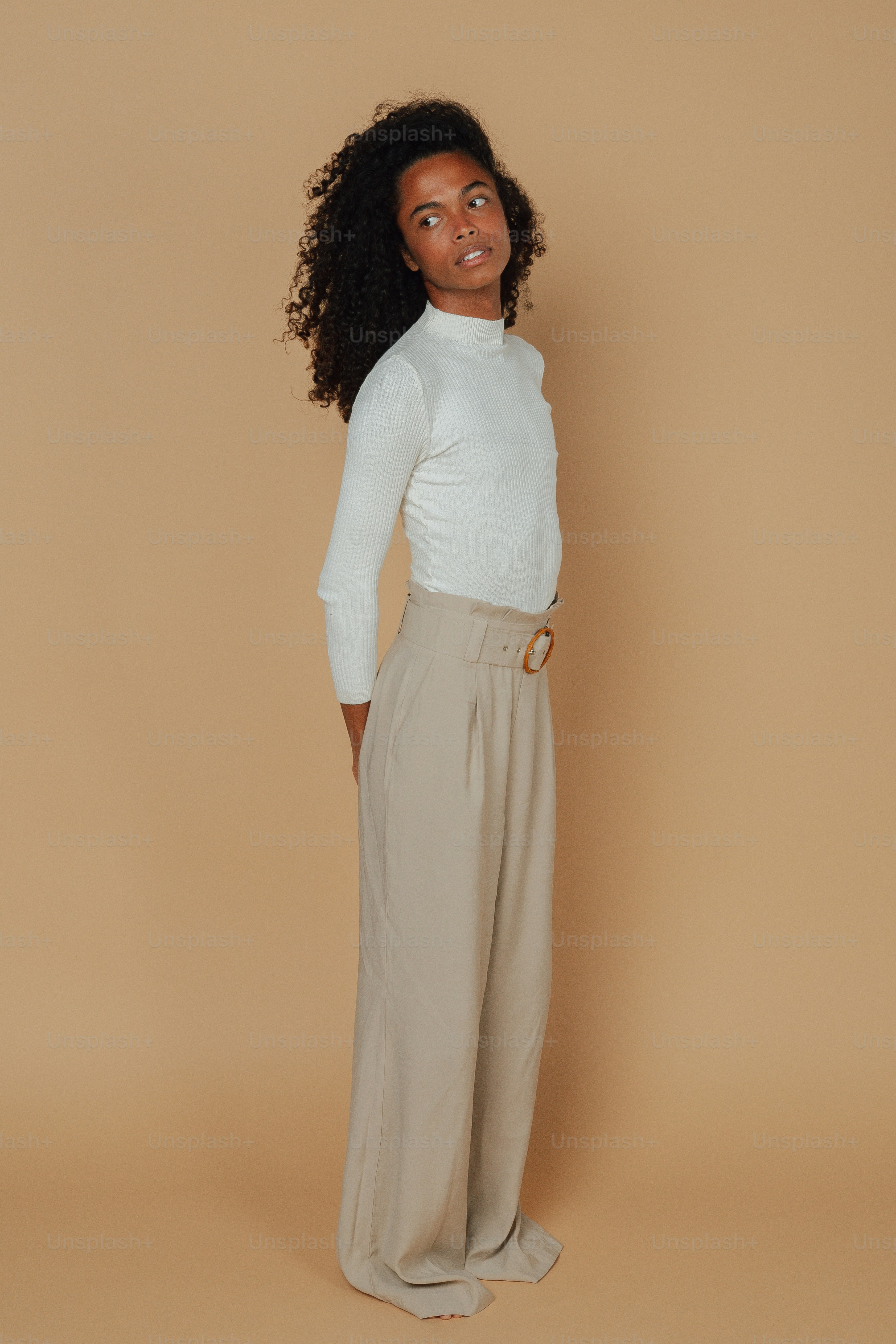 Una donna in un top bianco e pantaloni marrone chiaro