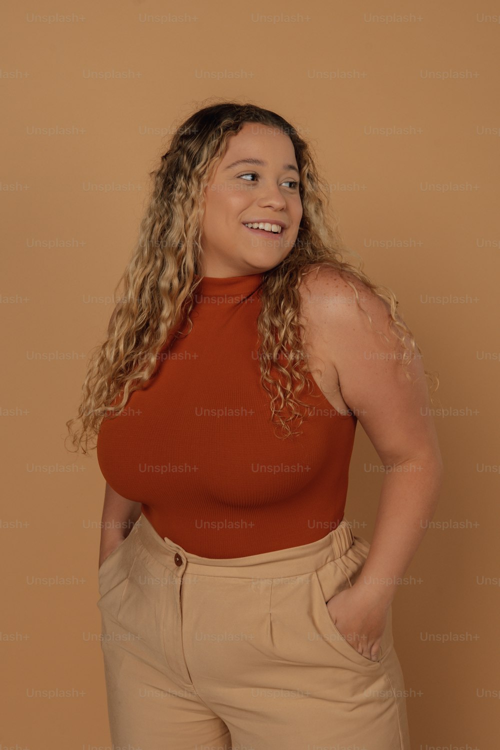 a woman wearing a red top and tan pants