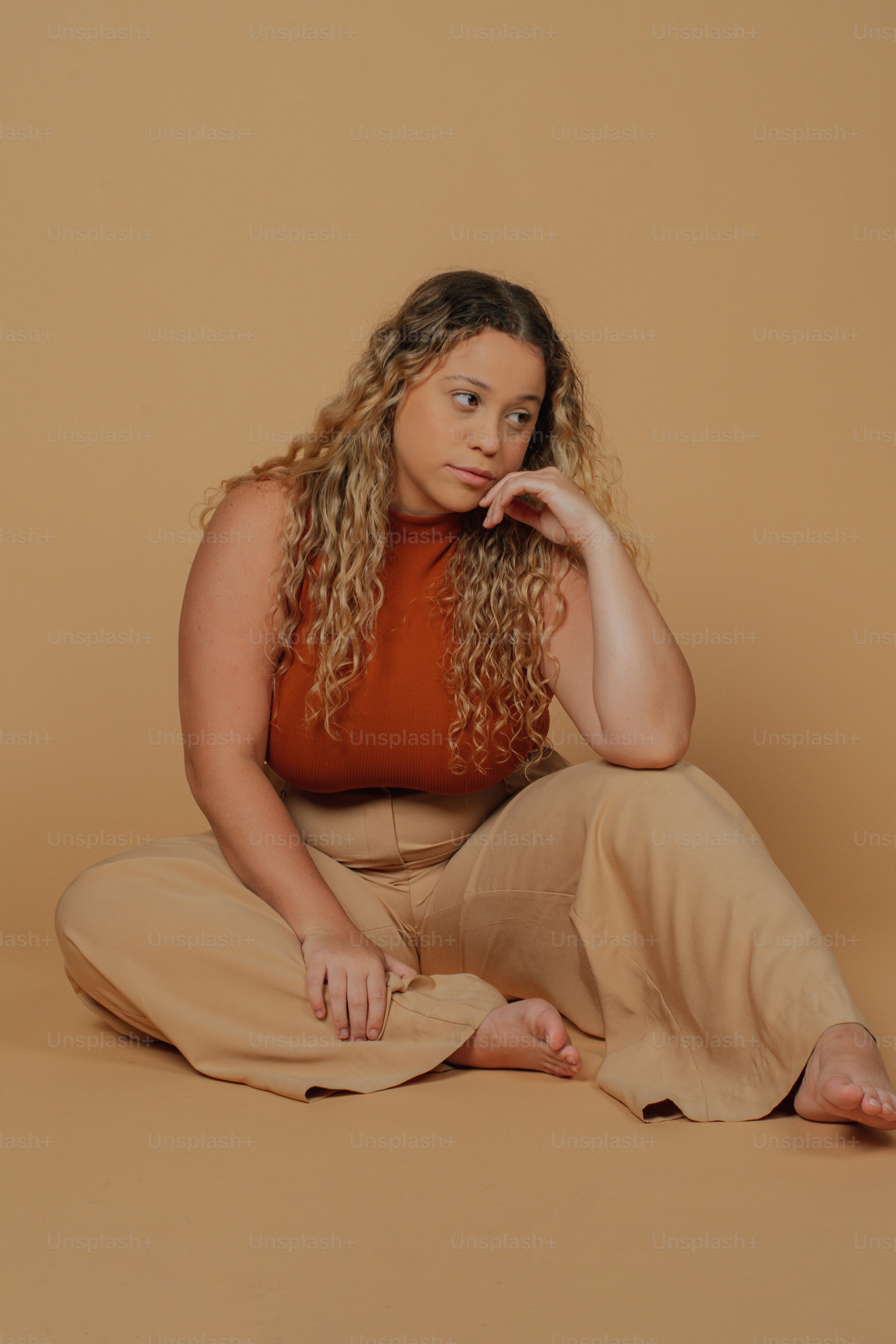 a woman sitting on the floor with her hand on her chin