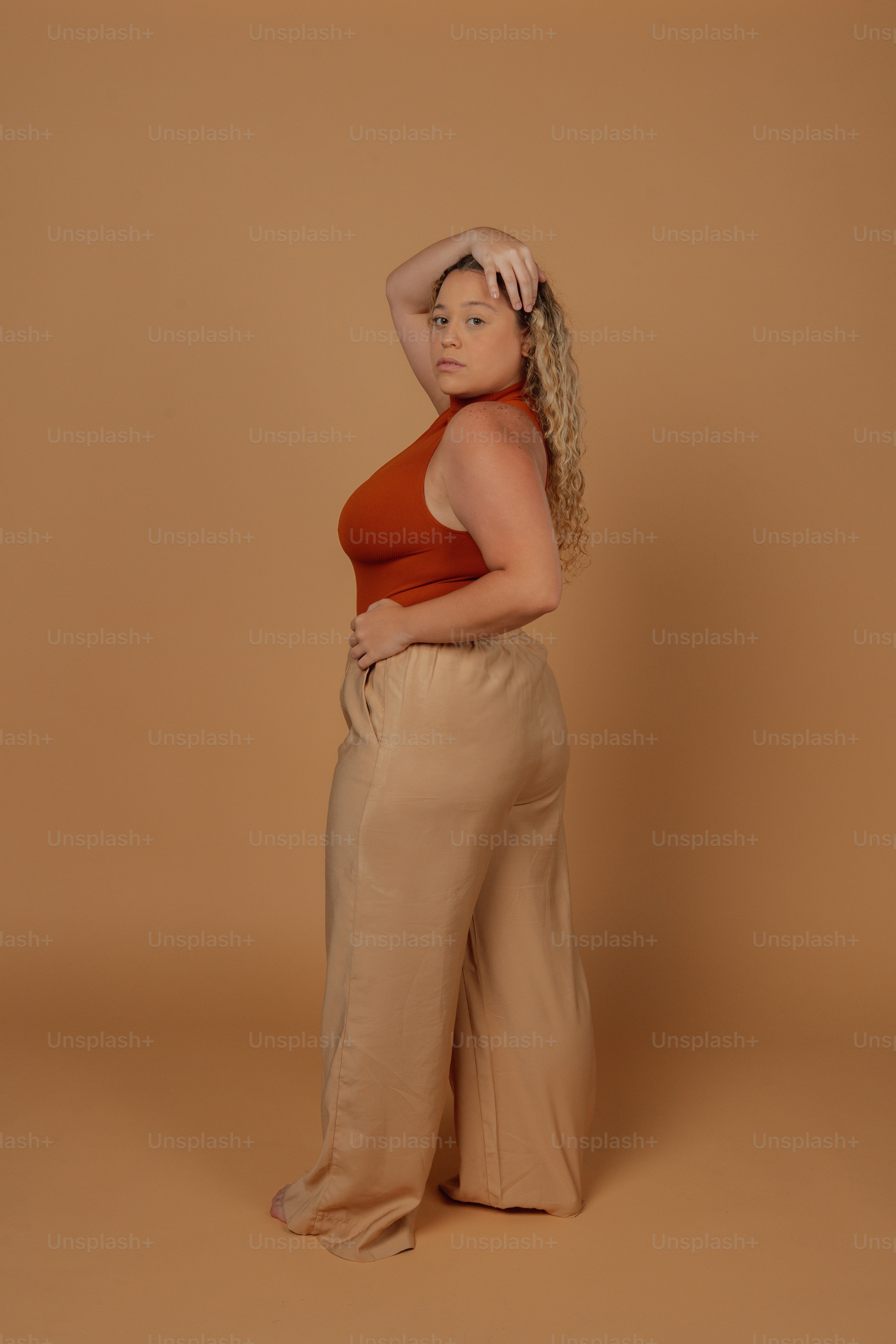 Una mujer con un top rojo y pantalones color canela