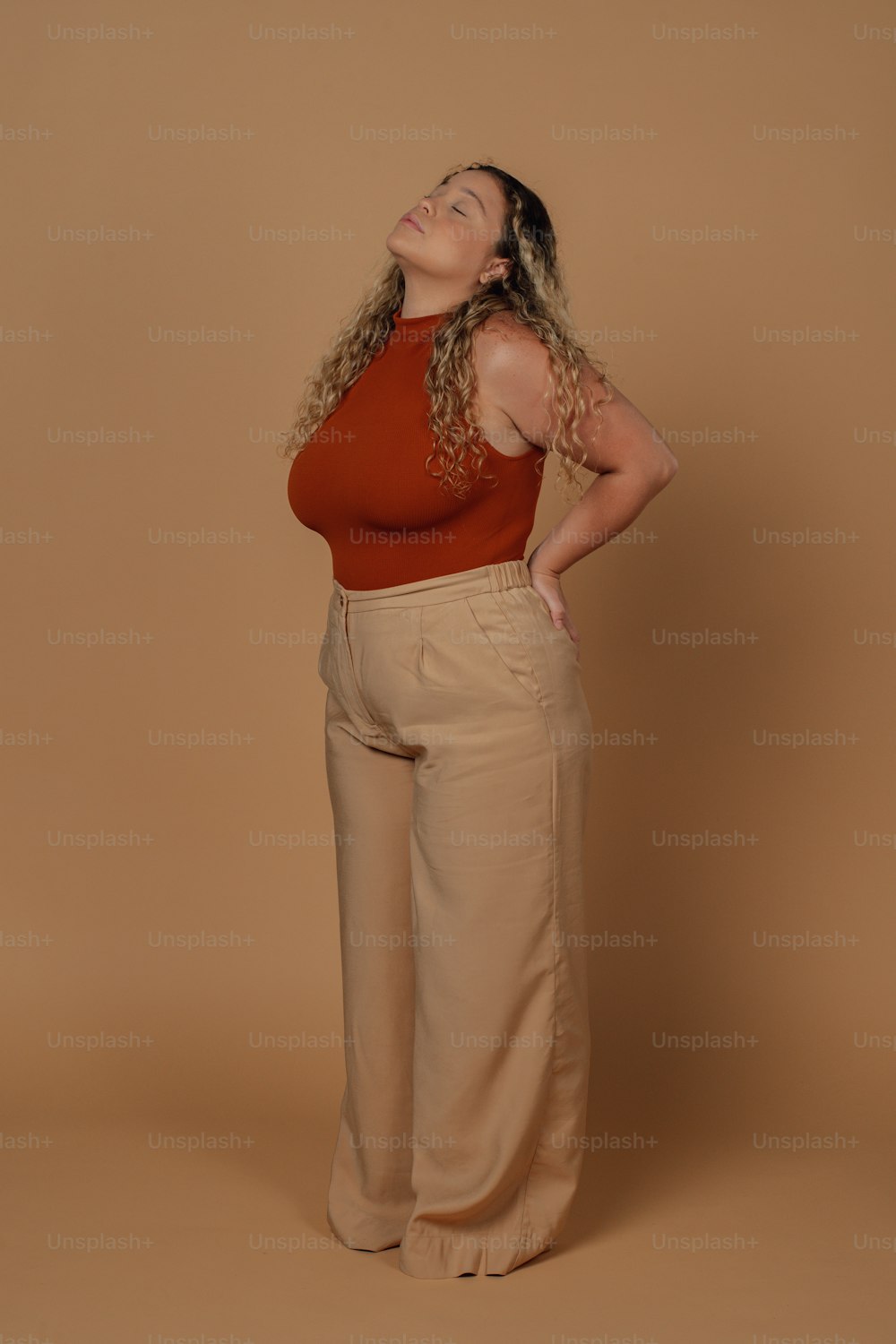 Una mujer con un top rojo y pantalones color canela