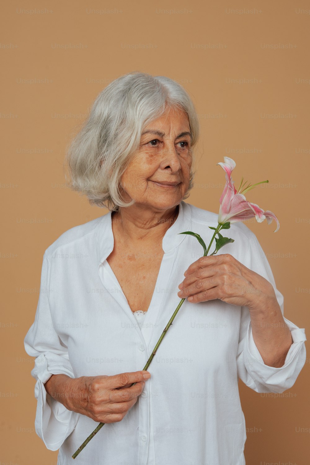Eine ältere Frau, die eine Blume in den Händen hält