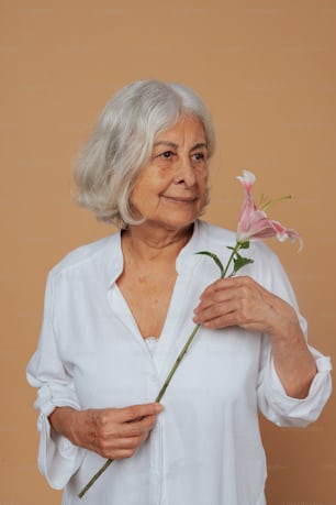 an older woman holding a flower in her hands