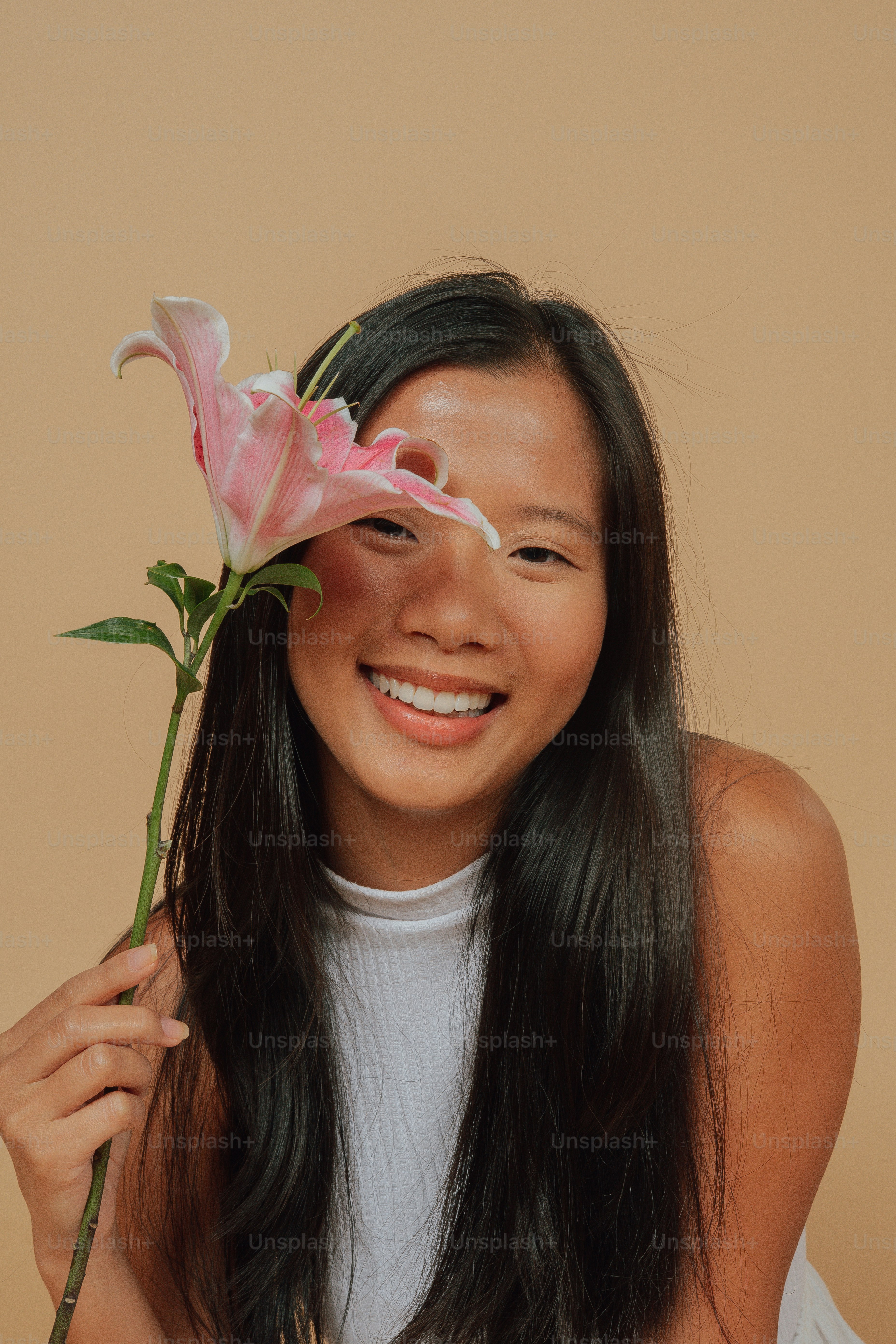 A woman holding a flower in front of her face photo – Happy Image on ...
