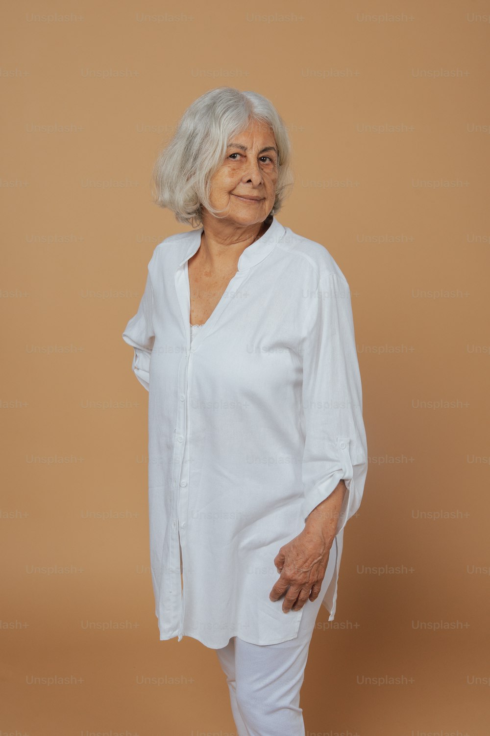 an older woman standing in front of a brown background